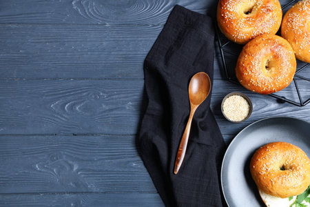 Stand and plate with tasty bagels on blue wooden background