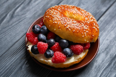 Plate of tasty bagel with butter and berries on blue wooden backgroundの写真素材