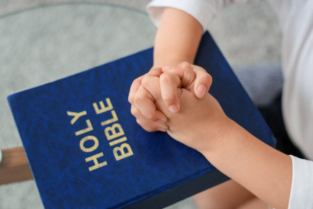 Cute little girl with Bible praying at home, closeupの写真素材