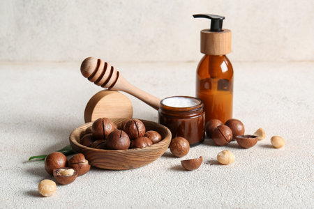 Macadamia nuts, bowl, honey stick, bottle and jar of cosmetic product on grunge backgroundの写真素材
