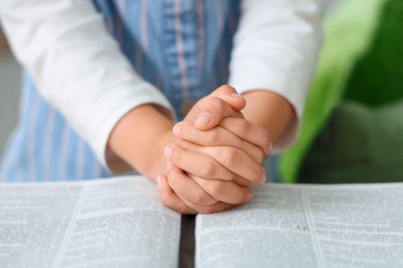 Cute little girl with open Bible praying at home, closeupの写真素材