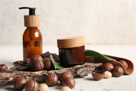 Beautiful composition with macadamia nuts, tree bark, jar and bottle of cosmetic product on grunge backgroundの写真素材
