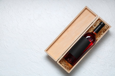 Wooden box with bottle of red wine on grunge white backgroundの写真素材