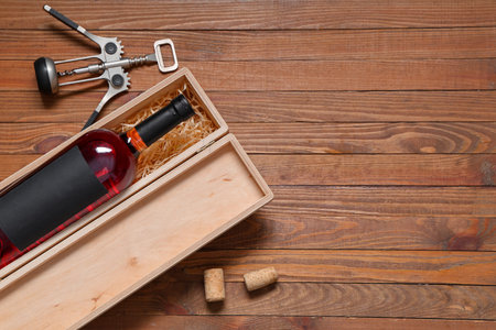 Box with bottle of wine and corkscrew on brown wooden backgroundの写真素材