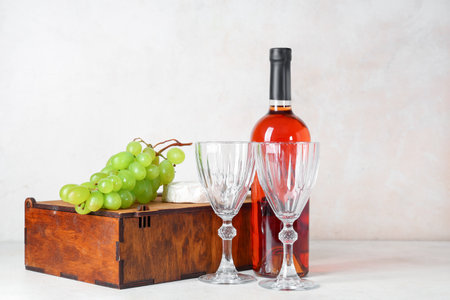 Box with bottle of wine, glasses, grapes and Camembert cheese on white grunge backgroundの写真素材