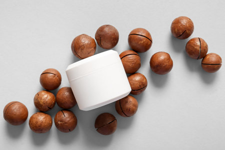 Macadamia nuts and jar of cosmetic product on gray background, closeupの写真素材