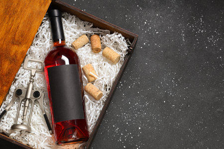 Box with bottle of wine, opener and corks on black grunge backgroundの写真素材