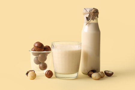 Glass and bottle of fresh macadamia milk on yellow backgroundの写真素材