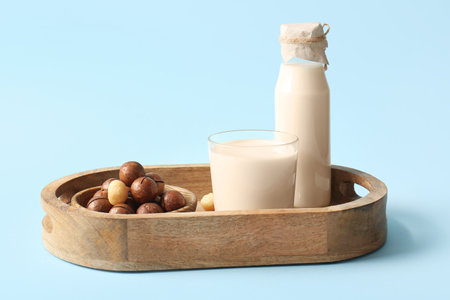Glass and bottle of fresh macadamia milk on blue backgroundの写真素材