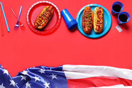 Tasty hot dogs with USA flags and cola on red background. American Independence Day celebrationの写真素材