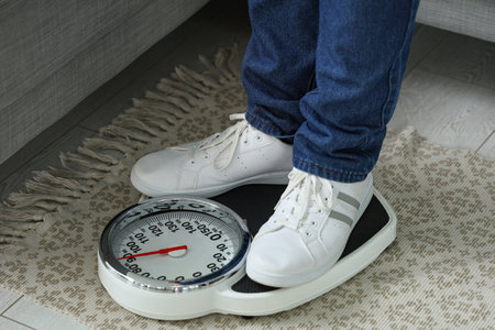 Young overweight man with scales at home. Weight gain conceptの写真素材