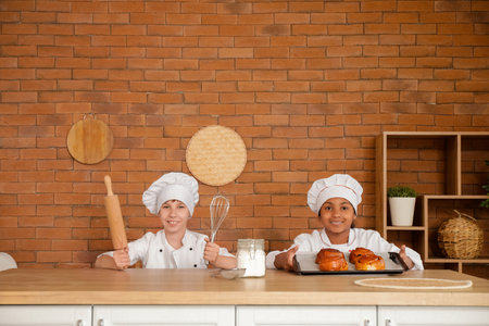 Teenage chefs with utensils and fresh pastry in kitchenの写真素材