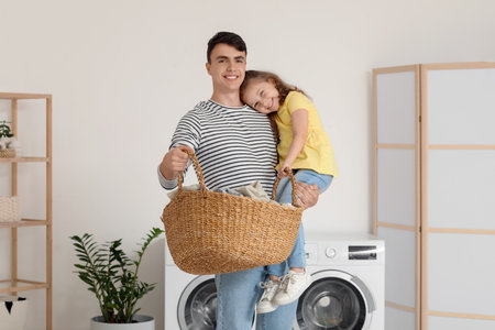 Young father and his daughter with laundry basket in bathroomの写真素材