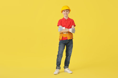 Teenage construction worker in hardhat on yellow backgroundの写真素材