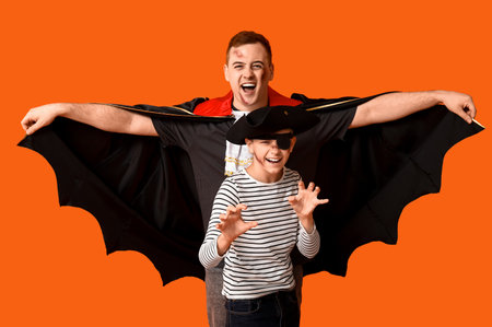Father with his son dressed for Halloween on orange backgroundの写真素材