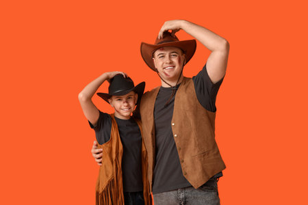Father with his son dressed for Halloween as cowboys on orange backgroundの写真素材