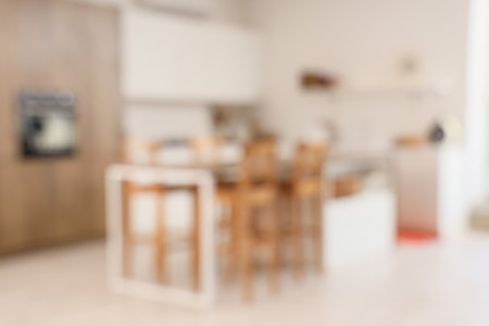 Blurred view of light kitchen with counters and dining tableの写真素材