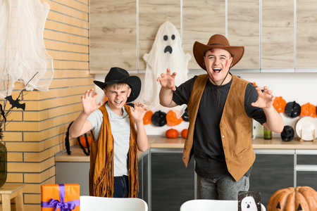 Scary father with his son dressed for Halloween as cowboys in kitchenの写真素材