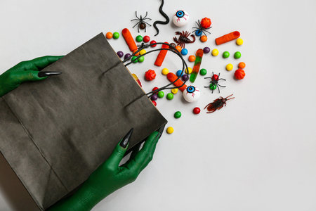 Witch holding shopping bag with candies and decorations for Halloween on gray backgroundの写真素材
