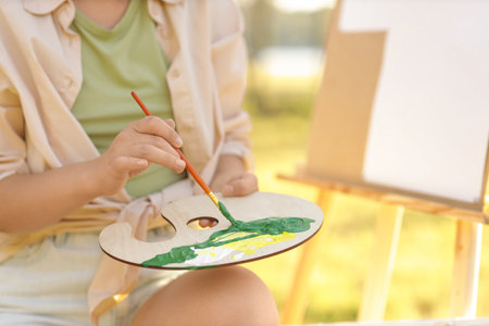 Beautiful artist with palette painting in park, closeupの写真素材