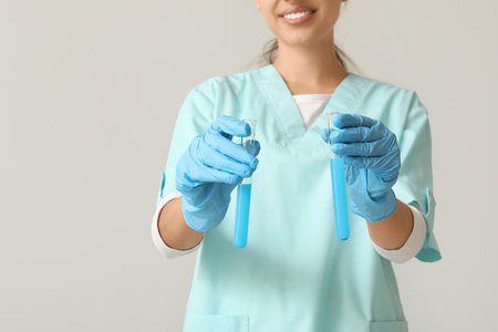Happy female young scientist with test tubes of water samples on gray background, closeupの写真素材