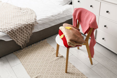 Warm sweaters with autumn leaves on chair in bedroomの写真素材