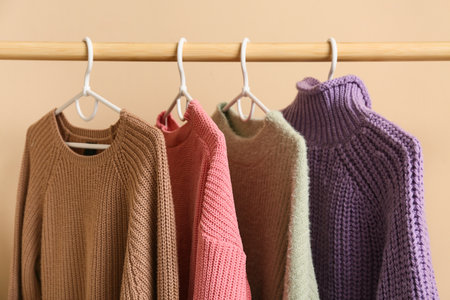 Rack with sweaters near beige wall, closeupの写真素材
