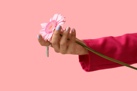 Female hand with beautiful manicure and gerbera flower on pink background, closeupの写真素材