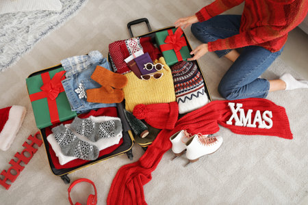 Female traveler packing Christmas gift into suitcase at home, top viewの写真素材