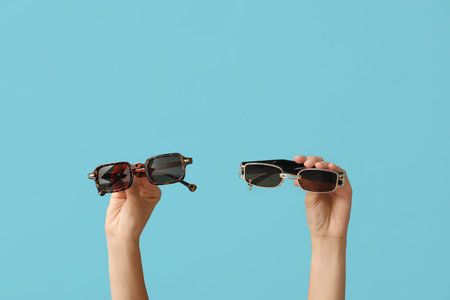 Female hands with different stylish sunglasses on blue background
