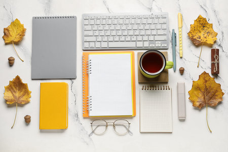 Notebooks with computer keyboard, tea cup and autumn decor on grunge background