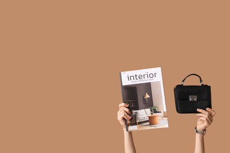 Female hands with magazine and stylish handbag on brown backgroundの写真素材