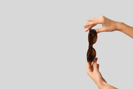 Female hands with leopard print sunglasses on gray backgroundの写真素材