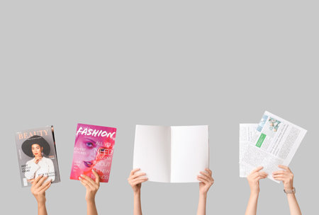 Female hands with different magazines and newspapers on gray backgroundの写真素材
