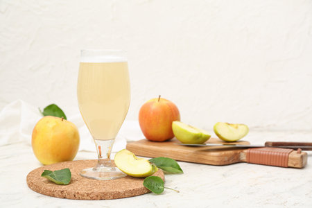 Glass of fresh apple kvass and wooden board with fruits on white backgroundの写真素材