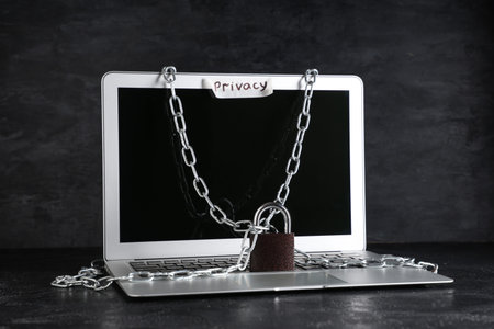 Laptop with chains and padlock on dark background. Cyber security conceptの写真素材