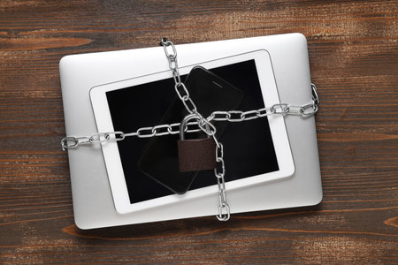 Modern gadgets with chains and padlock on wooden background. Cyber security conceptの写真素材