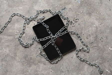 Tablet computer with padlock and chains on grunge background. Cyber security conceptの写真素材