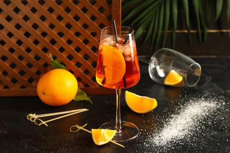 Glass of Aperol spritz cocktail and palm leaf on black tableの写真素材
