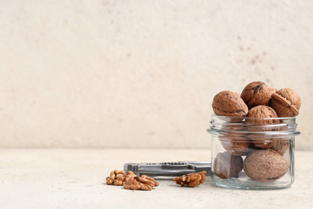 Jar with tasty walnuts and nutcracker on white backgroundの写真素材