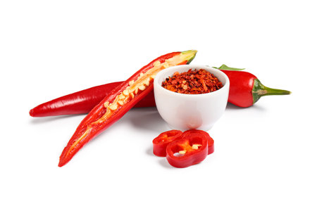 Fresh chili pepper and bowl with flakes on white background