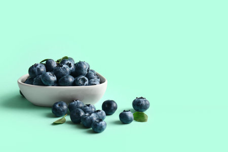 Bowl with ripe blueberry on turquoise background, closeupの写真素材