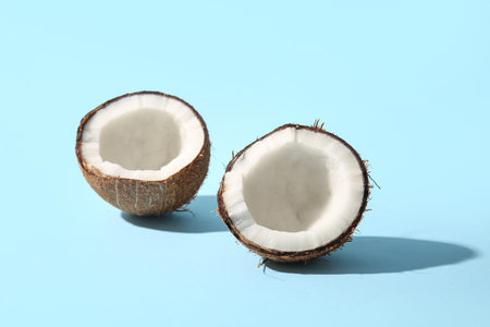 Halves of fresh coconut on blue background