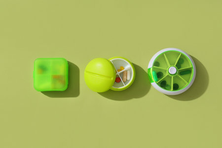 Plastic containers with pills on green background. Top view