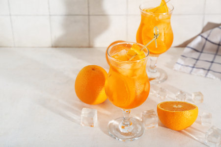 Glass of Aperol spritz cocktail and oranges on white tableの写真素材