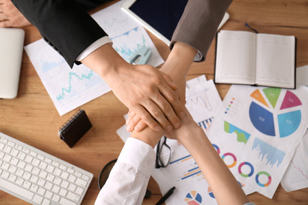 Business team putting hands together as symbol of unity during meeting in office, closeupの写真素材