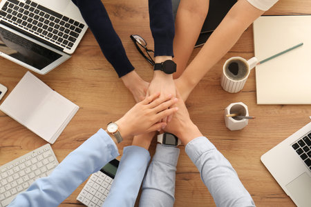 Business team putting hands together as symbol of unity during meeting in office, top view