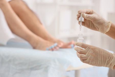 Young man getting professional pedicure with toe separator and cuticle oil on couch in spa salon, closeupの写真素材
