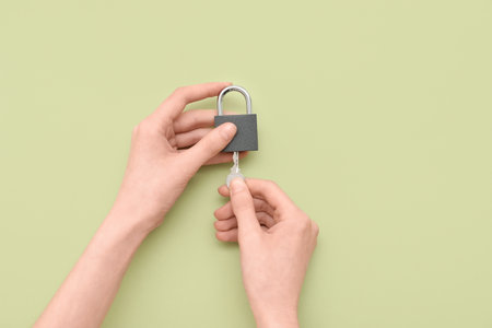 Hands with padlock and key on green backgroundの写真素材