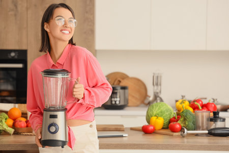 Young woman with blender in kitchenの写真素材
